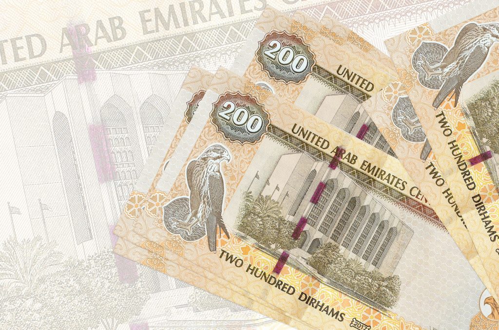 200 UAE dirhams bills lies in stack on background of big semi-transparent banknote. Abstract presen